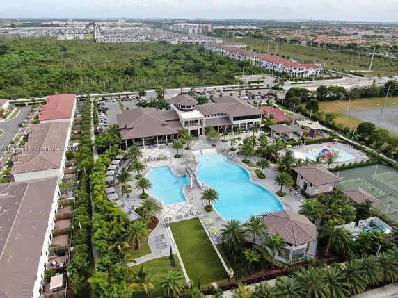 Aerial view of a large residential complex with a swimming pool and surrounding greenery.