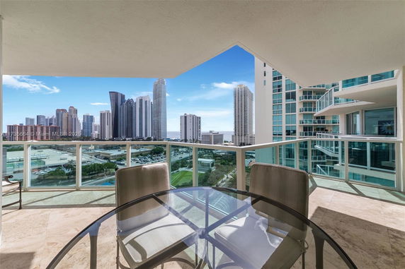 Panoramic view from a balcony of a high-rise building, showing a cityscape with several tall buildings.