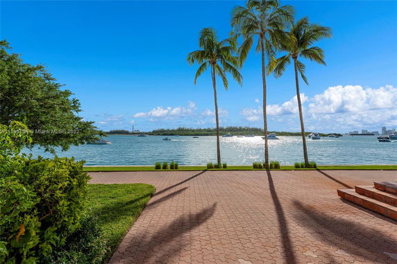 View of a waterfront area with palm trees and boats on the water.