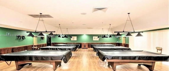 Room with multiple billiard tables and green walls