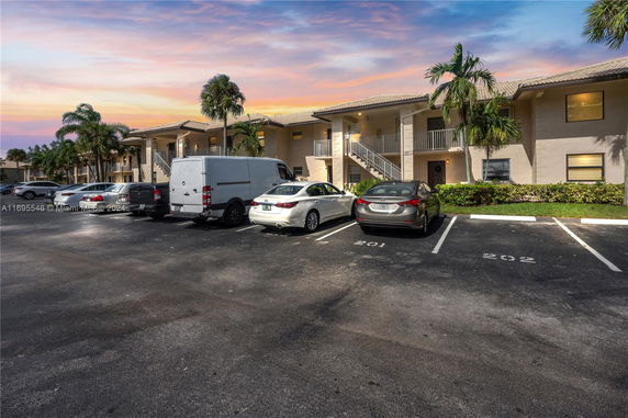 Outdoor parking area in front of a two-story residential building.