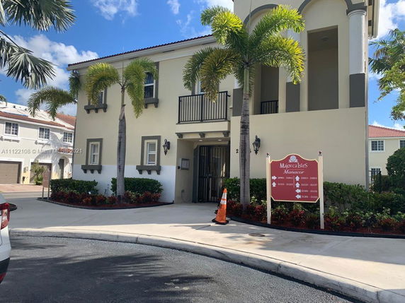 Front view of a two-story building with palm trees and a sign indicating Majorsca Isles Manacor.