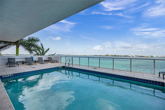 Rooftop pool area with lounge chairs and a view of the water.