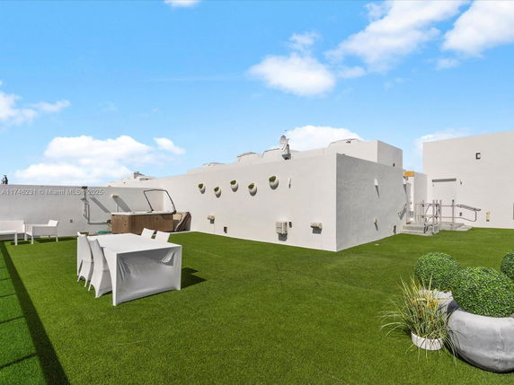 Rooftop area with artificial grass, seating, and a hot tub.