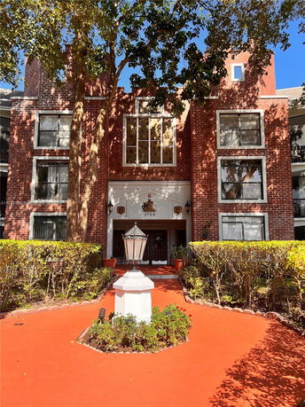 Front view of a multi-story brick building with large windows and entrance.
