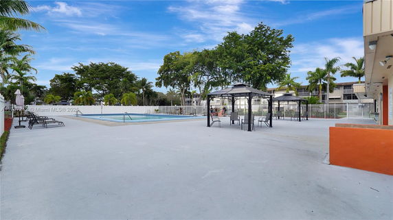 Outdoor swimming pool area with chairs and gazebos.