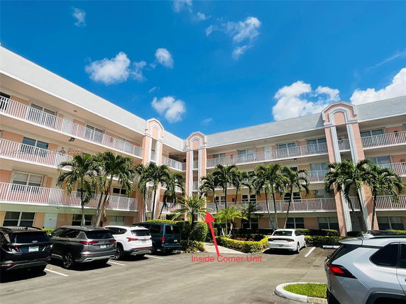 Front view of a multi-story building with balconies and parking area.