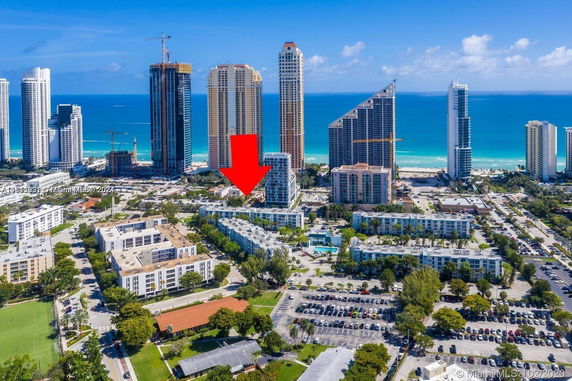 Aerial view of a coastal cityscape with tall buildings and a view of the ocean in the background.