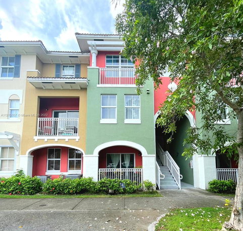 Front view of a three-story building with colorful facade and balconies.