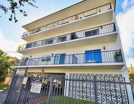 Front view of a multi-story residential building with balconies and a gated entrance.