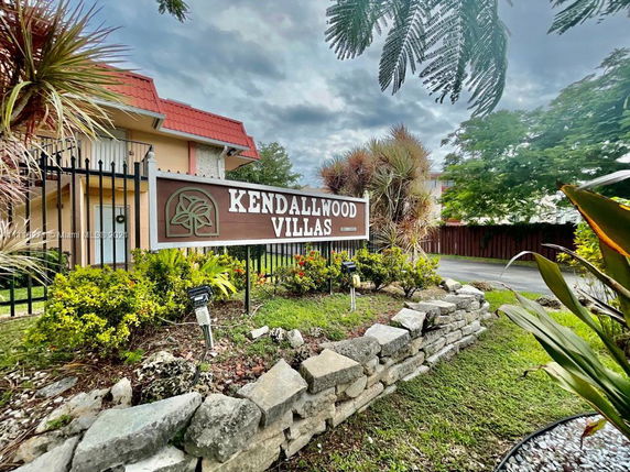 Front view of Kendallwood Villas building with a sign and landscaped garden.
