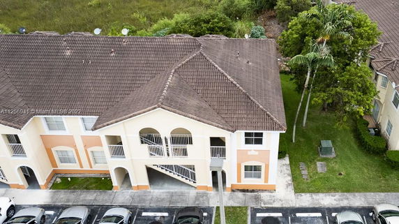 Front view of a two-story building with a tiled roof and parking area.