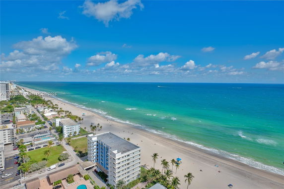 Aerial view of a beachfront area with buildings and a sandy beach along the ocean.