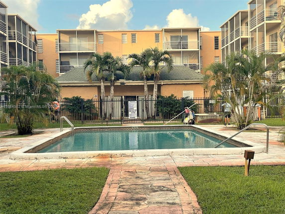 Swimming pool area in front of a multi-story residential building.