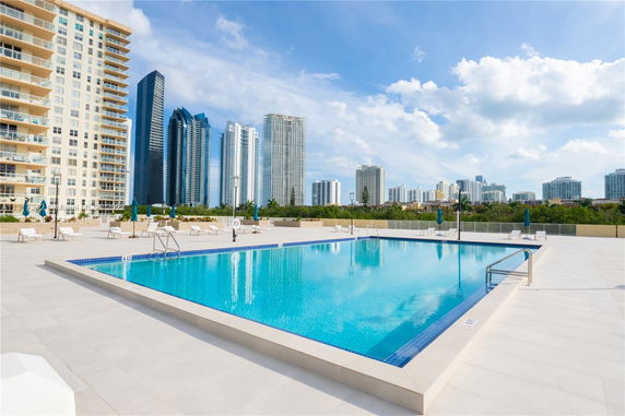 Outdoor swimming pool area with city skyscrapers in the background.