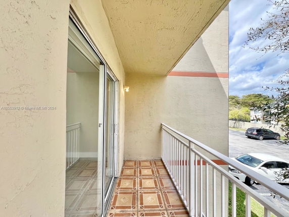 Balcony view from a building with a parking lot and surrounding area in sight.