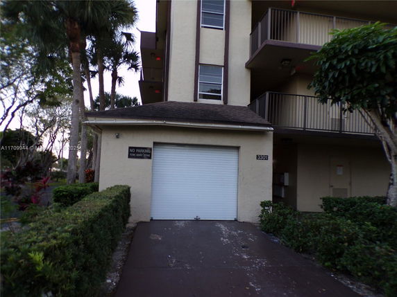 Front view of a building with a garage door and balconies.