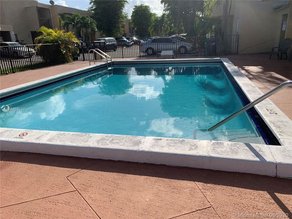 Outdoor swimming pool with a ladder and surrounding patio area.