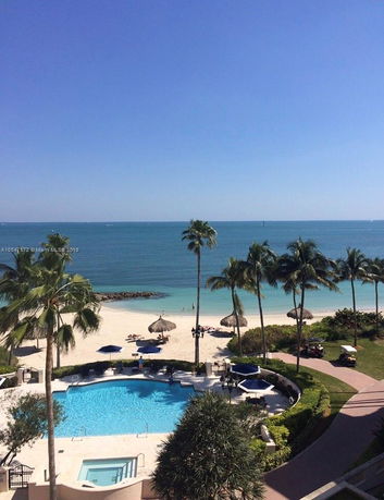 Panoramic view of a beach and pool area from a higher vantage point.