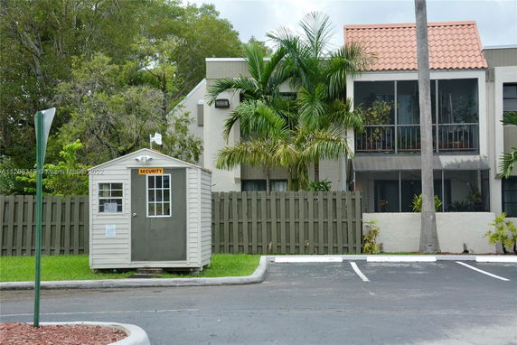 Front view of a building with a parking area and a small security kiosk.