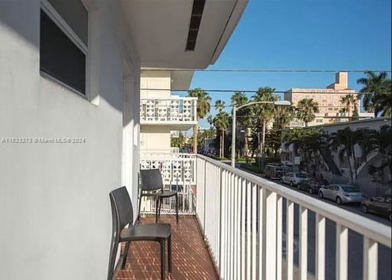 Balcony view showing urban surroundings with palm trees and buildings.