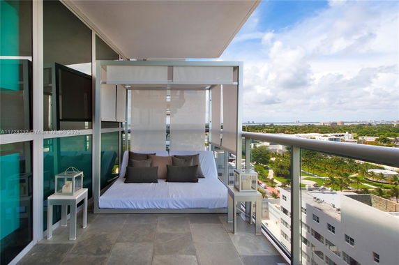 Balcony view from a high-rise building with seating area and scenic cityscape.
