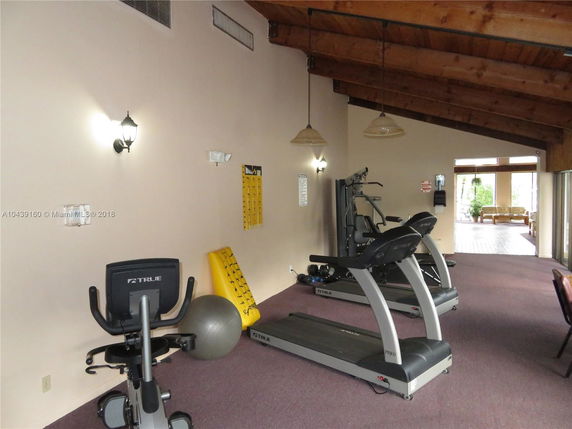 Indoor gym area with exercise equipment and wooden ceiling.