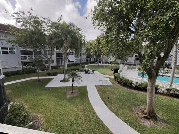 View of a landscaped courtyard with pathways and a swimming pool, surrounded by buildings.