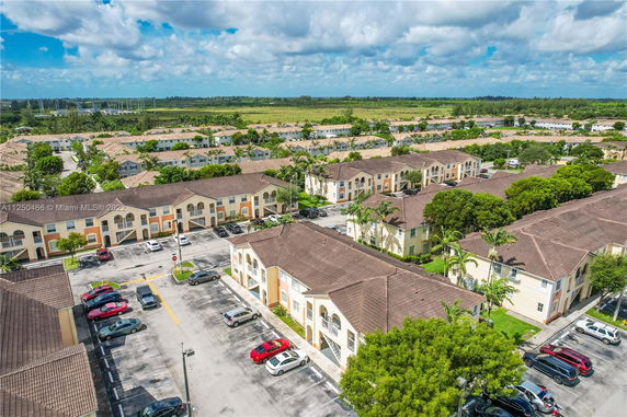 Aerial view of residential apartment complex with parking areas and green surroundings.