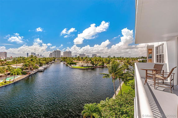 Panoramic view of a waterway with buildings and palm trees.