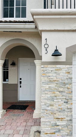 Front entrance of a house with an arched doorway and stone wall accents.