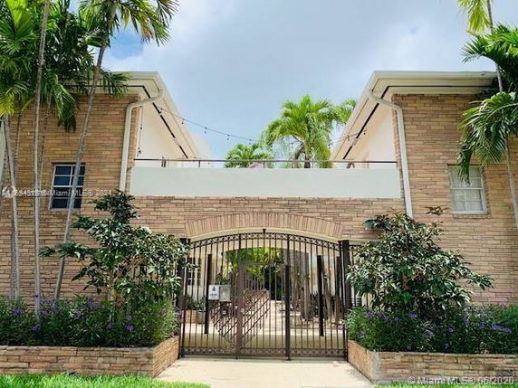Front view of a two-story brick building with a gated entrance and a balcony.