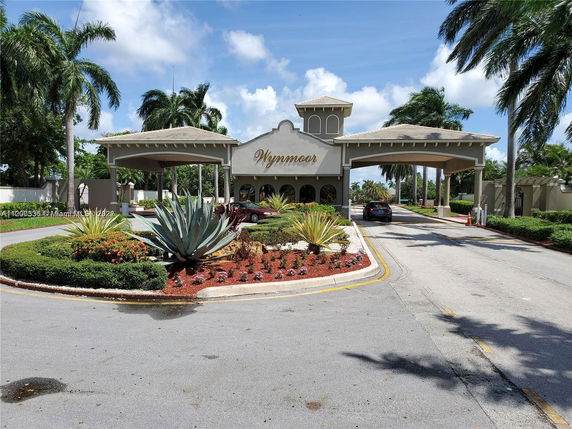 Front view of a gated community entrance with a covered driveway and landscaped area.