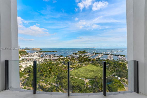 Panoramic view from a building showing a marina, greenery, and the ocean.