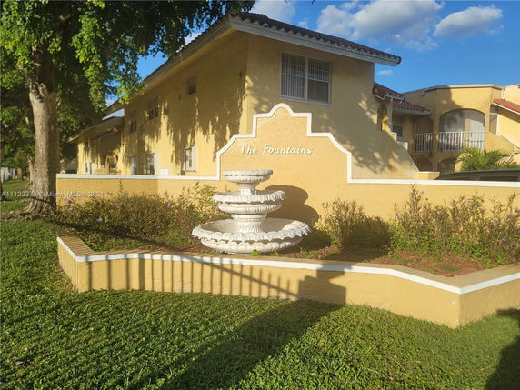 Front view of a two-story building with a decorative fountain and yellow exterior.