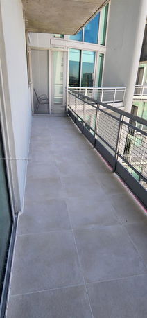 Balcony with tiled flooring and metal railing, overlooking an urban area.