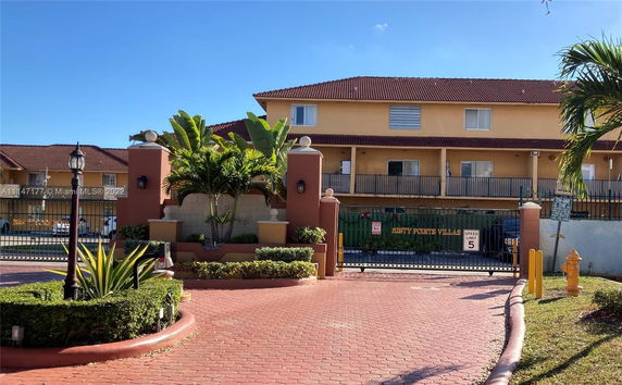 Front view of a multi-story villa complex with yellow exterior and red-tiled roof.