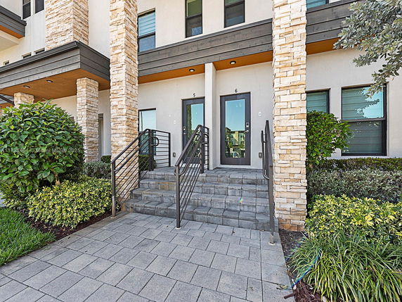 Front view of a modern multi-story building with stone pillars and entrance steps.