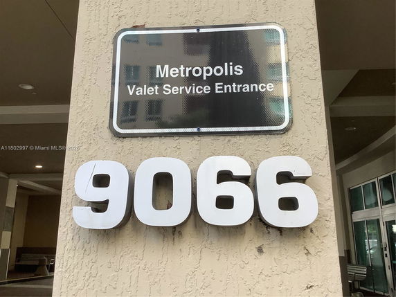 Exterior view of a building entrance with signage indicating 'Metropolis Valet Service Entrance' and large numbers '9066'.