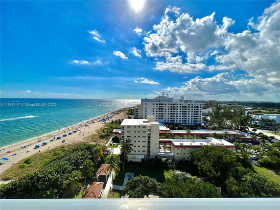 Panoramic view of buildings along a beachfront with ocean and sky in the background.