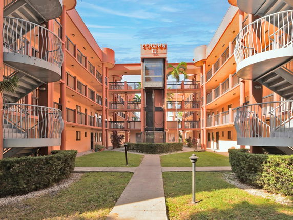 Front view of an apartment building with multiple balconies and a central walkway.