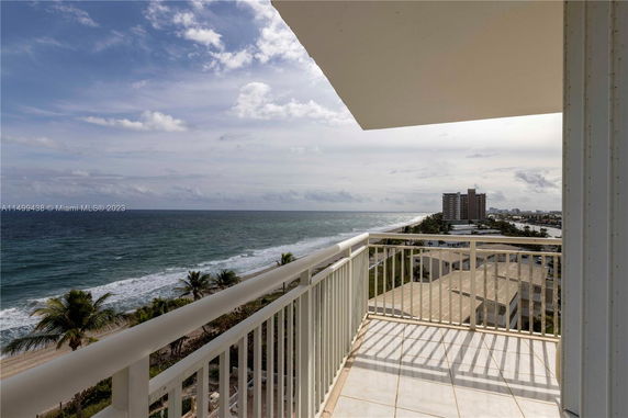 View from a building showing the ocean and coastline with palm trees and distant buildings.