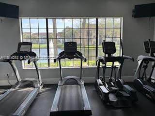 Indoor gym area with treadmills and exercise machines in front of a large window.