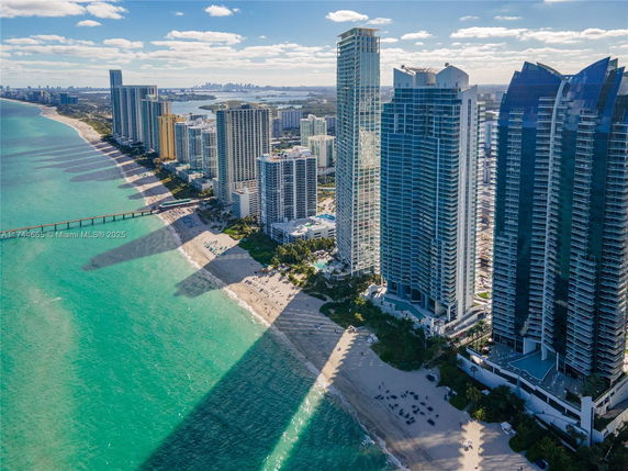 Aerial view of a coastline lined with skyscrapers and a beach.