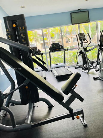 Indoor fitness area with workout machines including treadmills and an exercise bench.