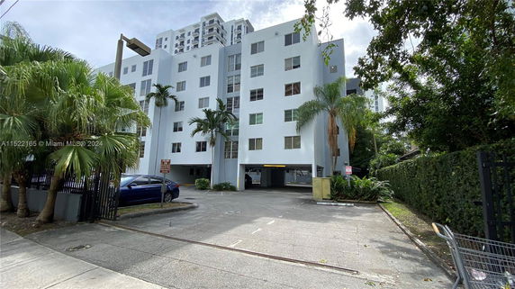 Front view of a multi-story residential building with parking area below.