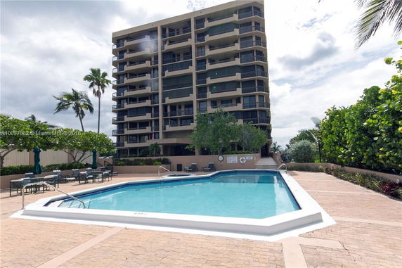 Front view of a multi-story building with balconies and an outdoor swimming pool.