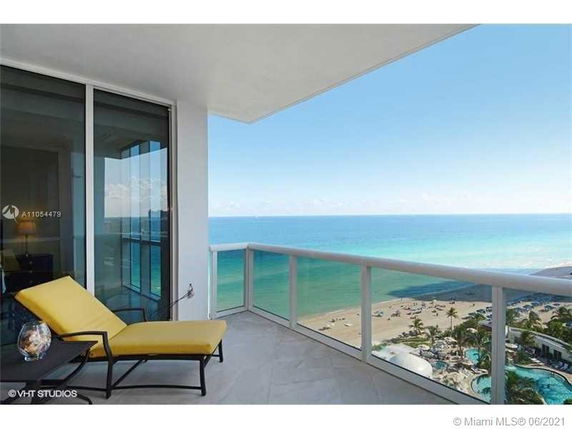 View from a balcony overlooking the ocean and beach below.