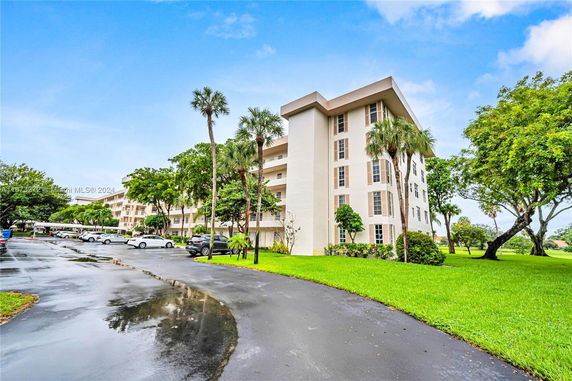 Front view of a multi-story residential building with a parking area.