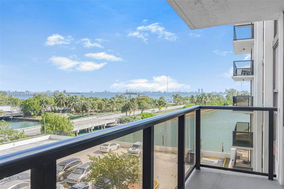 View from a balcony overlooking a waterway and city skyline in the distance.